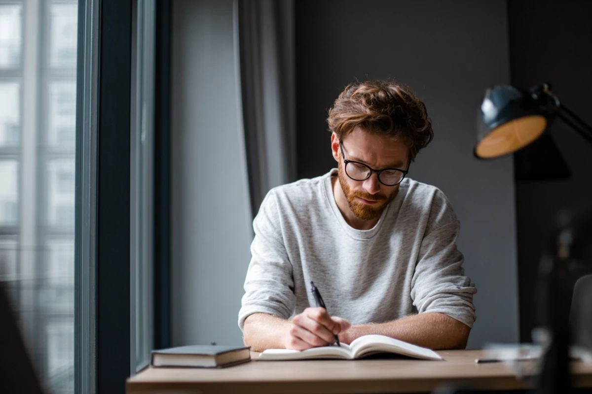 Man writing in journal at desk