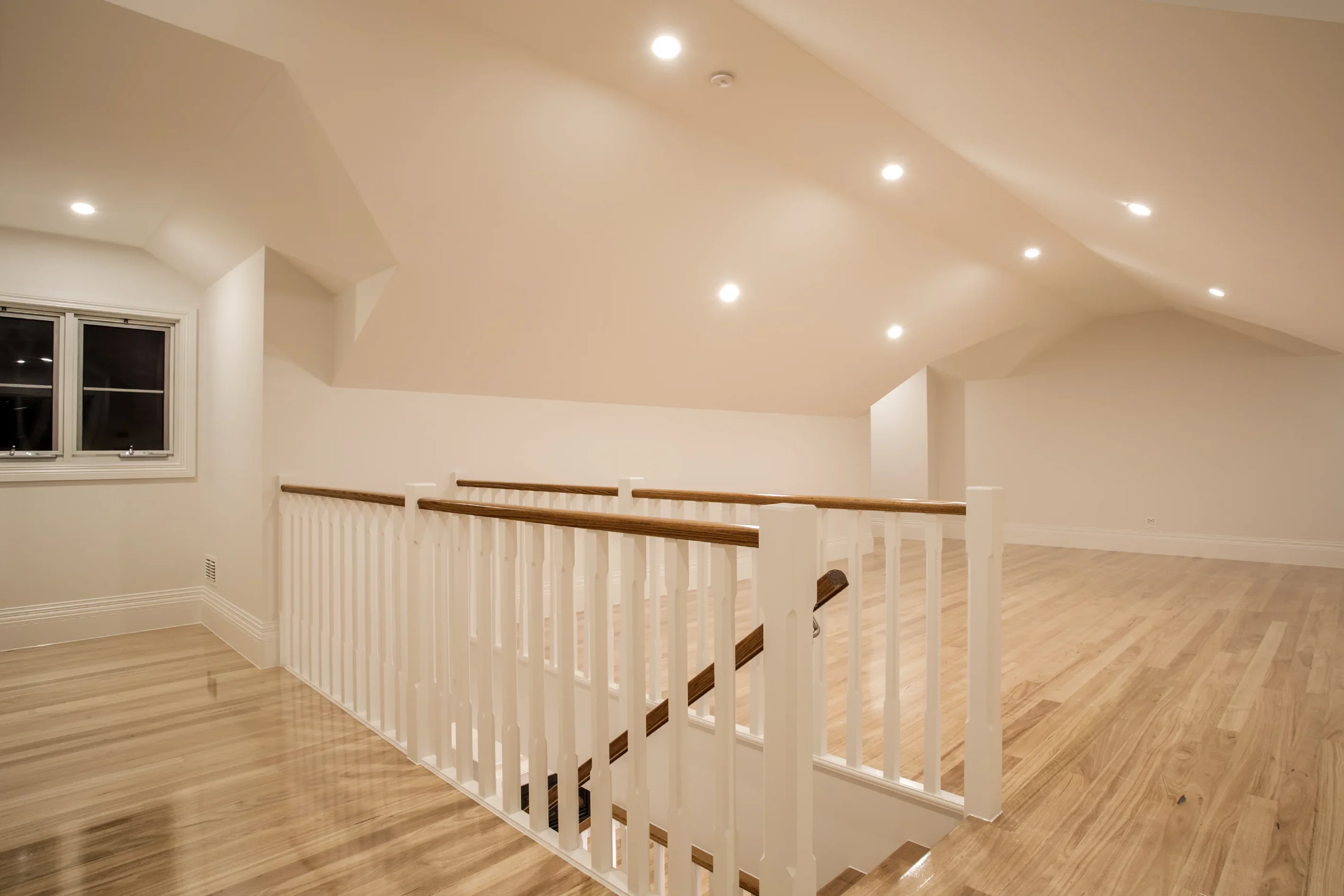 Upstairs retreat landing with a vaulted ceiling, white timber balustrade with oak rail and light timber flooring