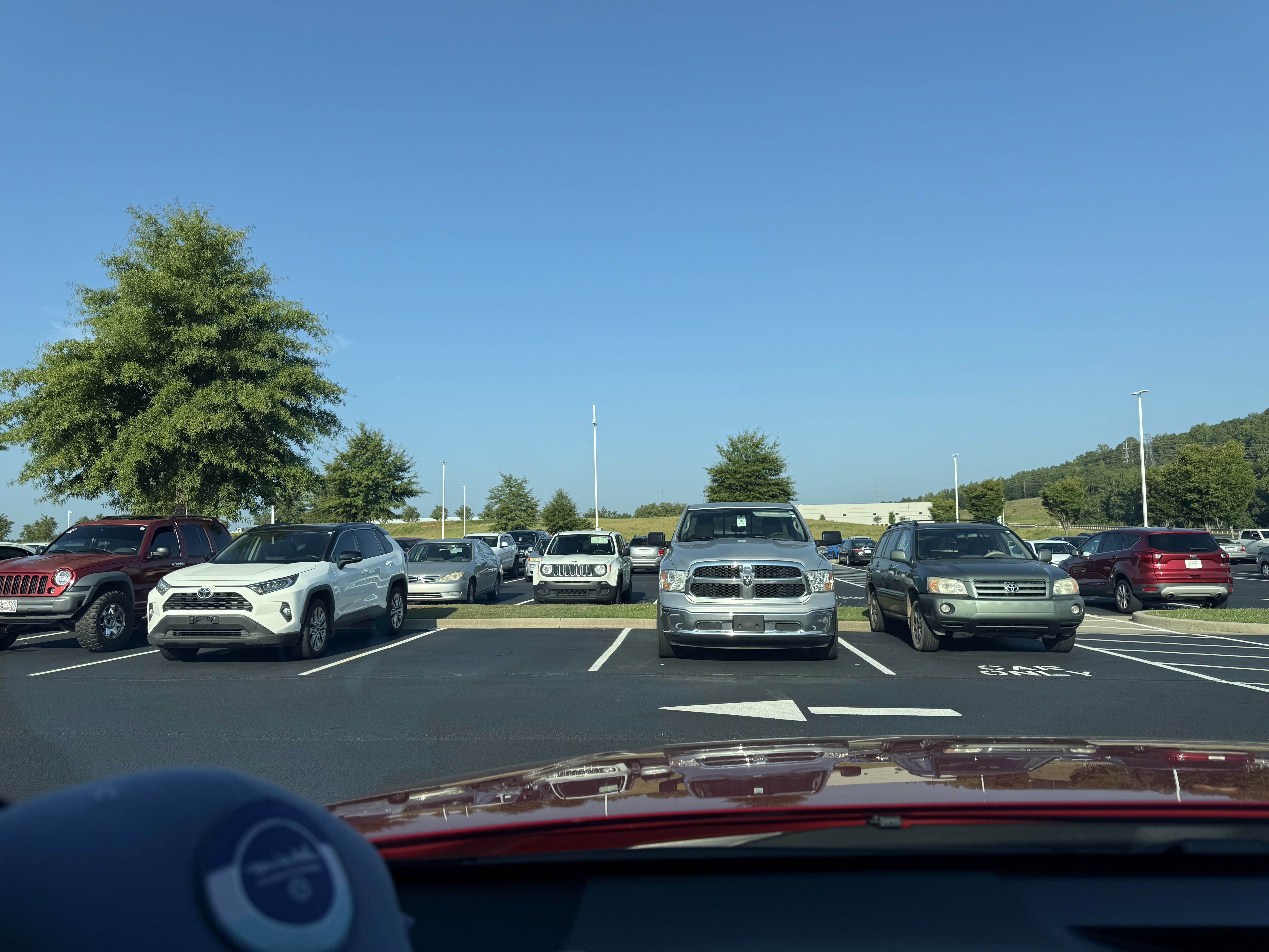 View from inside car looking through a window at a parking lot filled with cars, representing reflection, moving forward, and leaving the past behind.