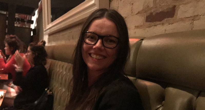 A photo of a woman sitting on a sofa near some other people.