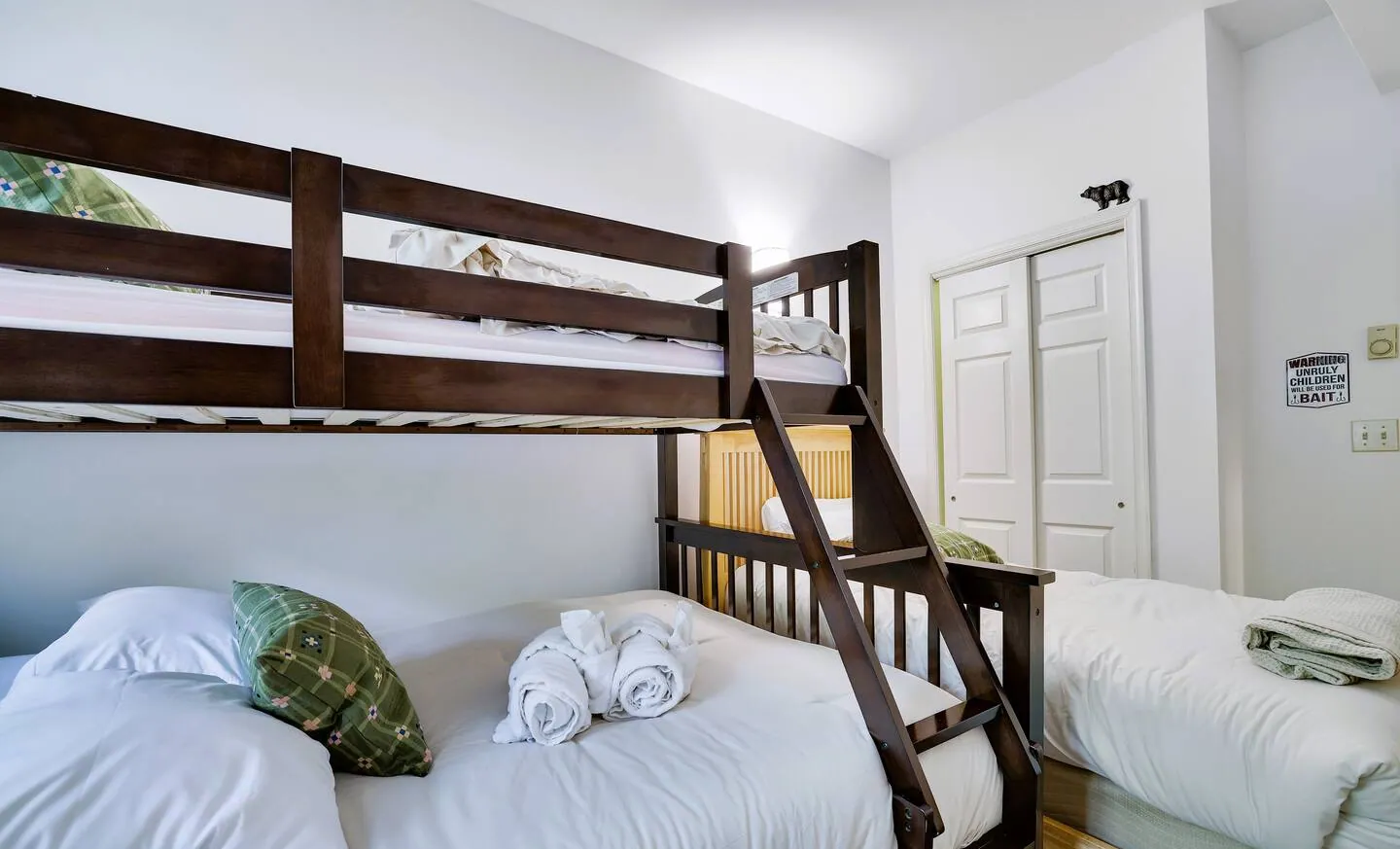 Twin over full bunk bed beside a single bed with white linens at Pop's Place