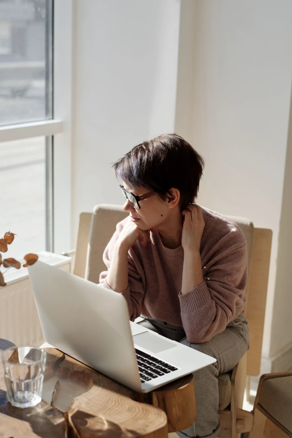 Woman sitting at a table with a laptop, looking tense as she prepares to speak or present.