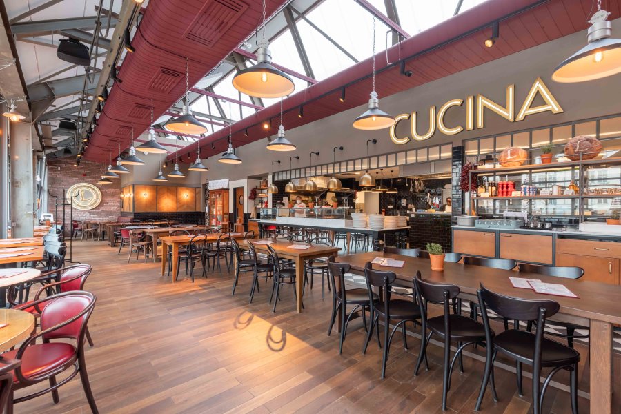 Cucina Restaurant Innenraum, helles Ambiente mit Holztischen und Stühlen. Gastronomie Konzept.