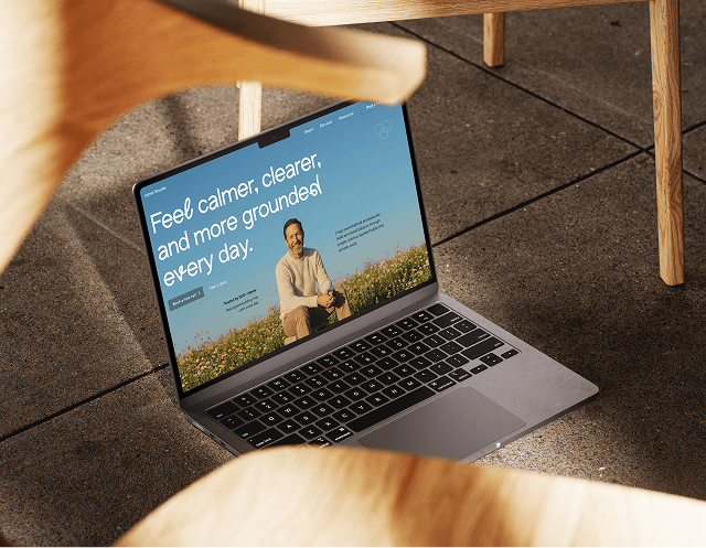 Laptop showing a wellness website with a smiling man in a green field.