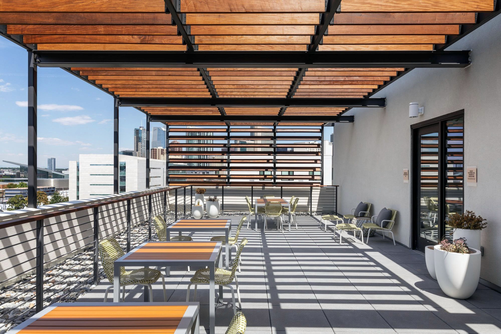 Modern rooftop patio with tables, chairs, and city view.