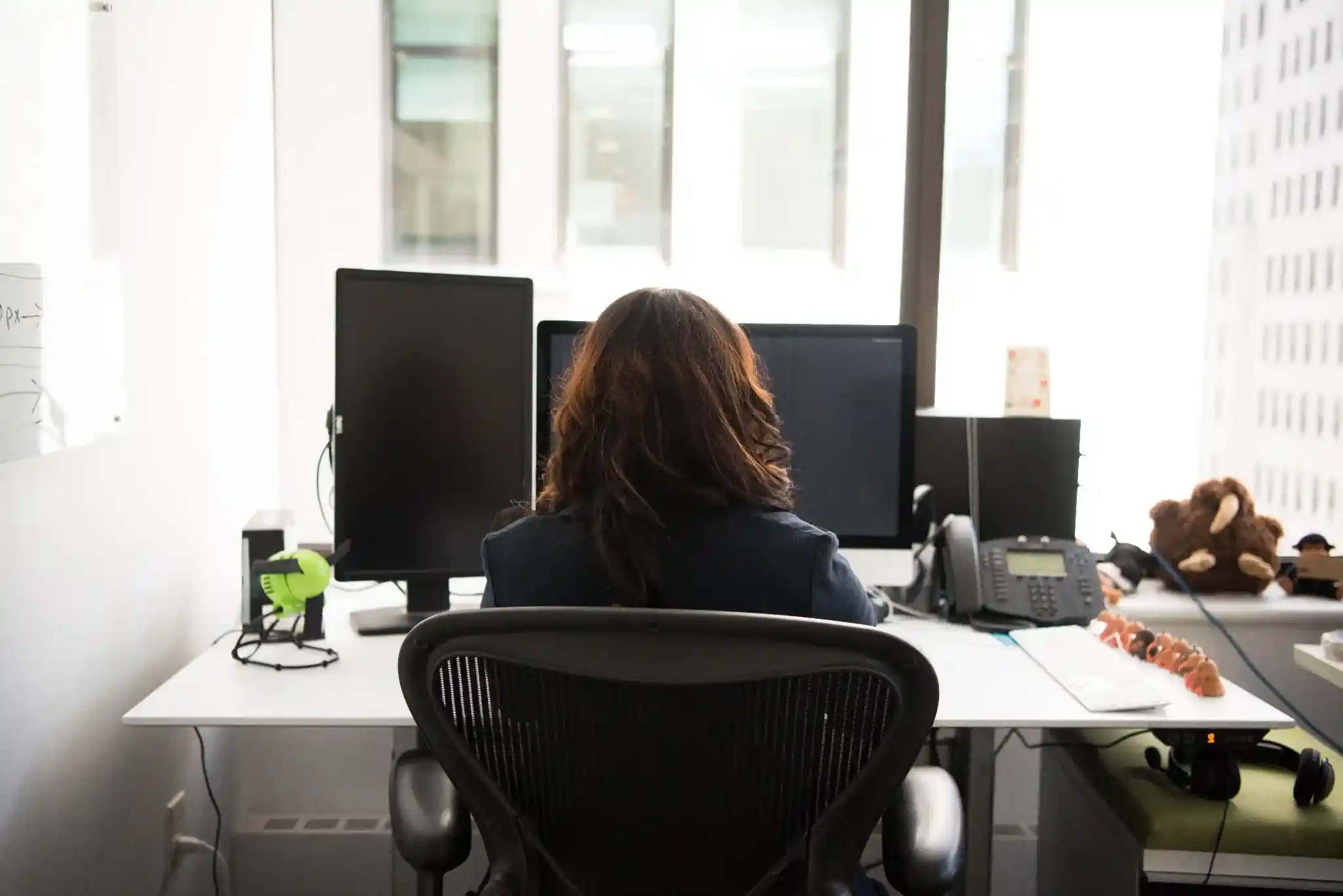 Professional working at a multi-monitor office workstation, representing web development, digital technology, and business productivity services.