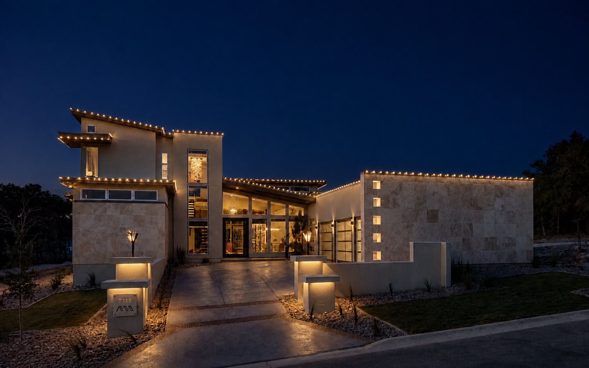 Permanent roofline lighting following every plane of a modern home at dusk