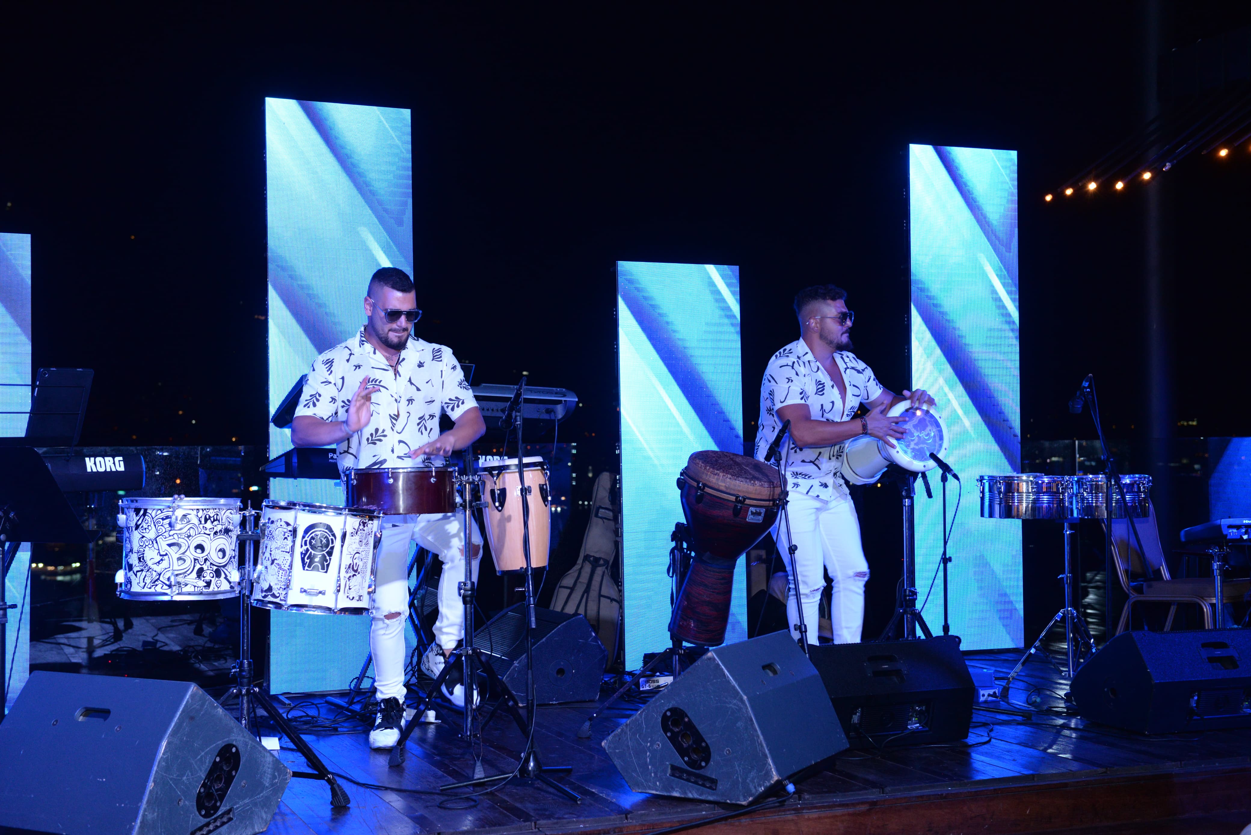 A confident person with short, styled hair and a leather jacket poses against a dark backdrop.
