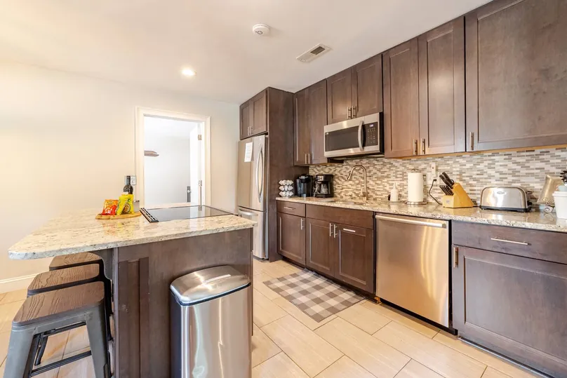 Kitchen with dark wood cabinets, a granite island with stools and stainless appliances