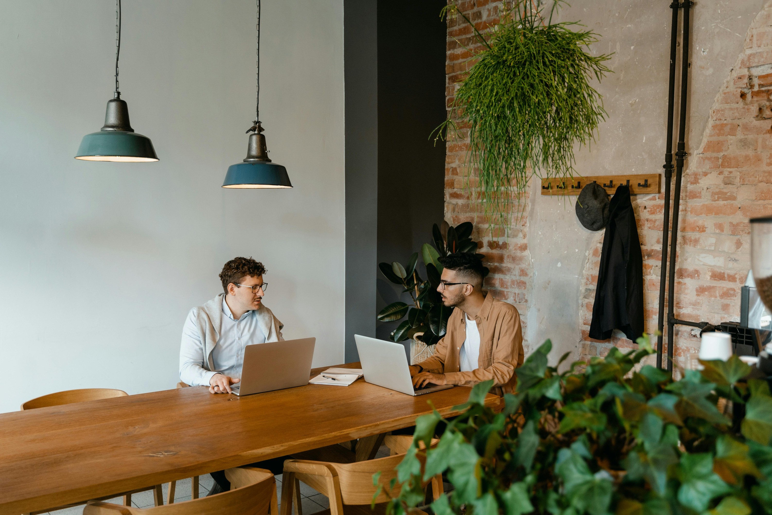 Zwei Freelancer sitzen am Tisch und planen ein Kundenprojekt am Laptop – typische Situation im Projektmanagement.