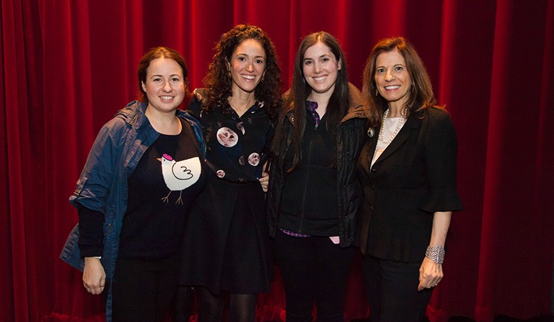 group photo of four women with a red curtain behind them