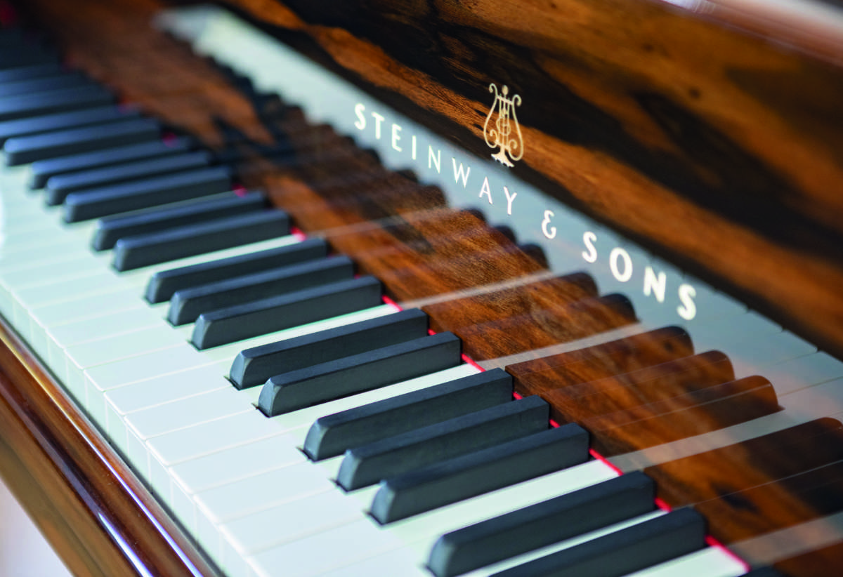 A close-up view of the Steinway & Sons grand piano keyboard, showcasing the fine craftsmanship and stunning wood grain detail.
