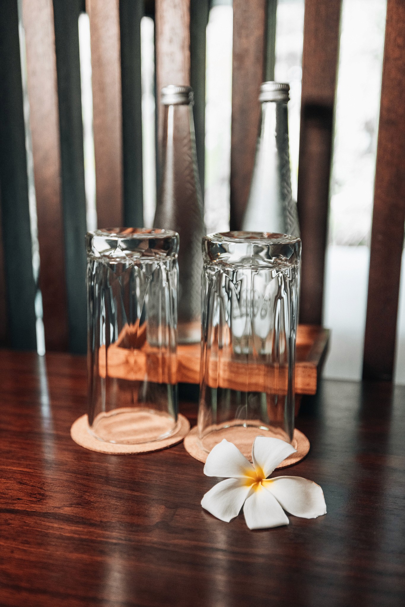 Zwei elegant platzierte Gläser auf einem Holztisch im Restaurant des Ning Resort Ubud