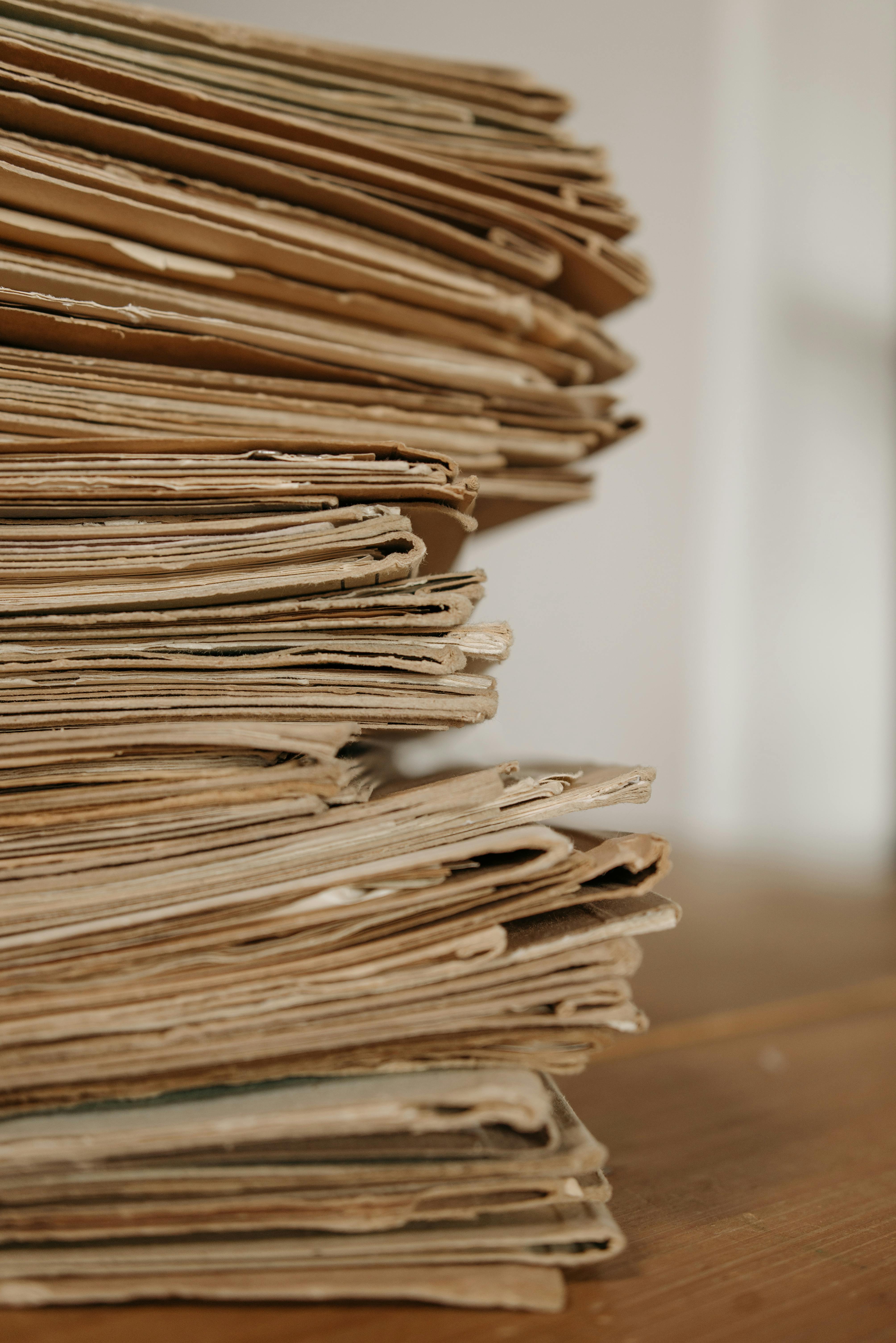 Close-up of a tall stack of documents on a wooden surface.