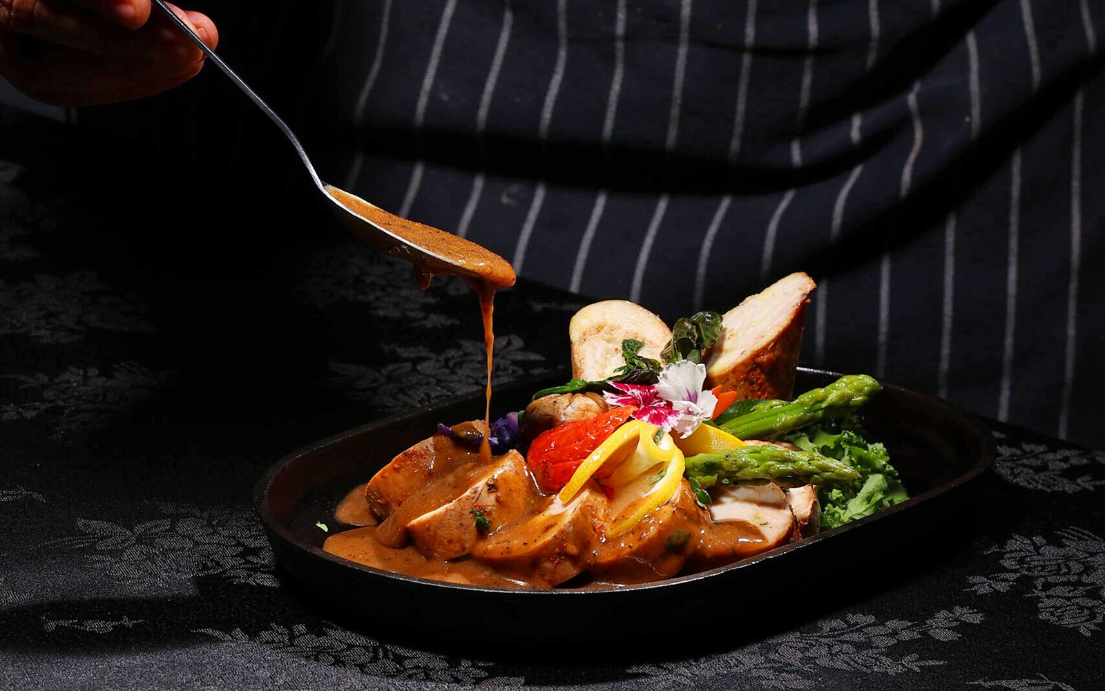 Chef voegt saus toe aan een gerecht in restaurant ARAS, KL Tower, Kuala Lumpur.