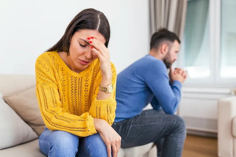 A couple facing away from each other stressed from an argument on a couch