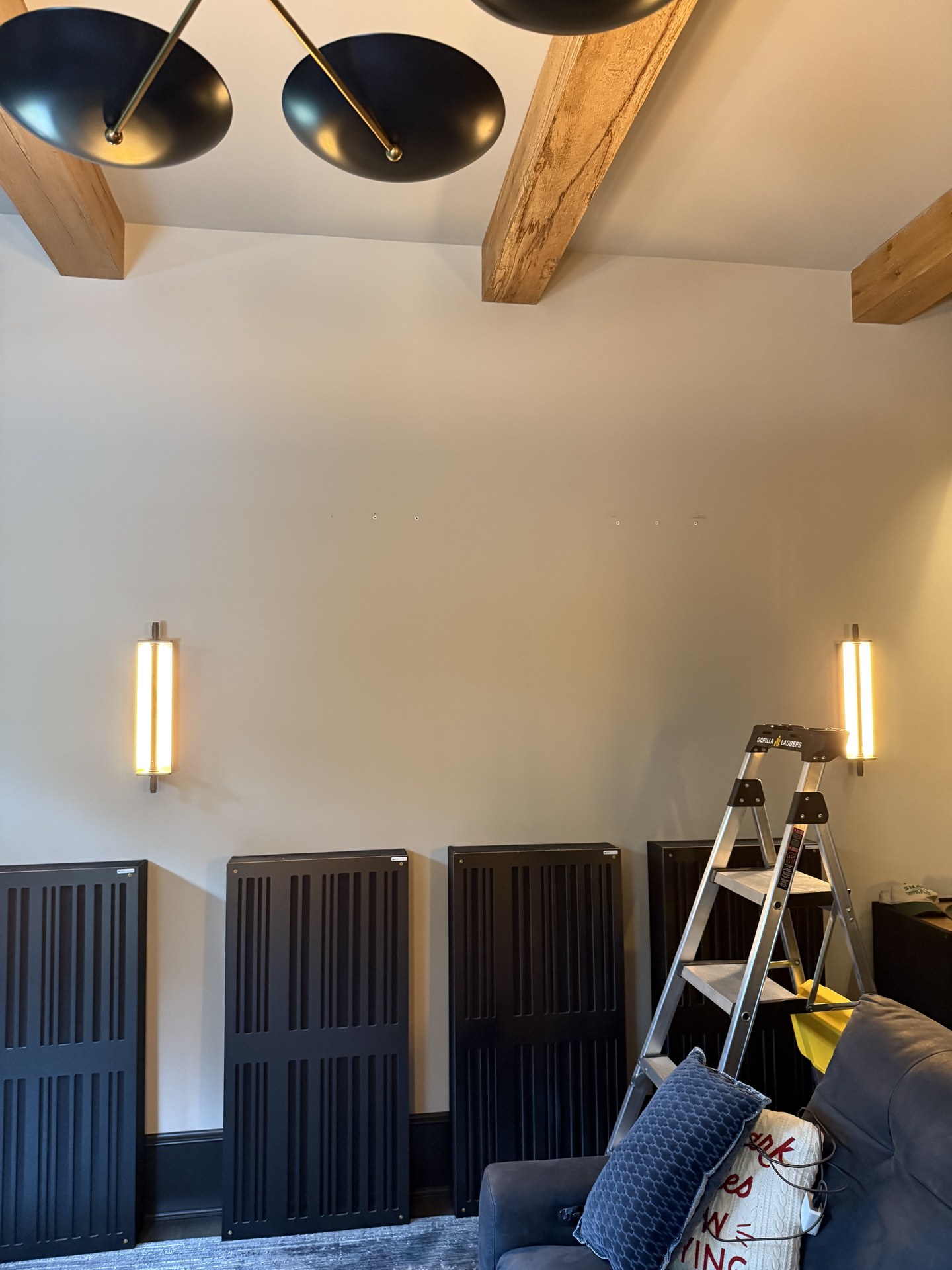 Acoustic panels resting against a wall beneath lights before mounting