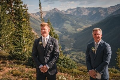 The groom and officiant wait at the mountain ceremony site.