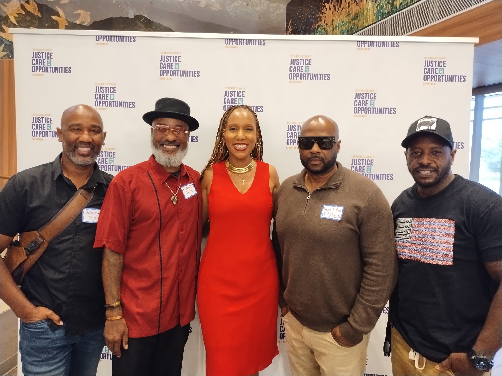 Woman practicing yoga warrior pose on a wooden platform surrounded by forested mountains in early morning light.