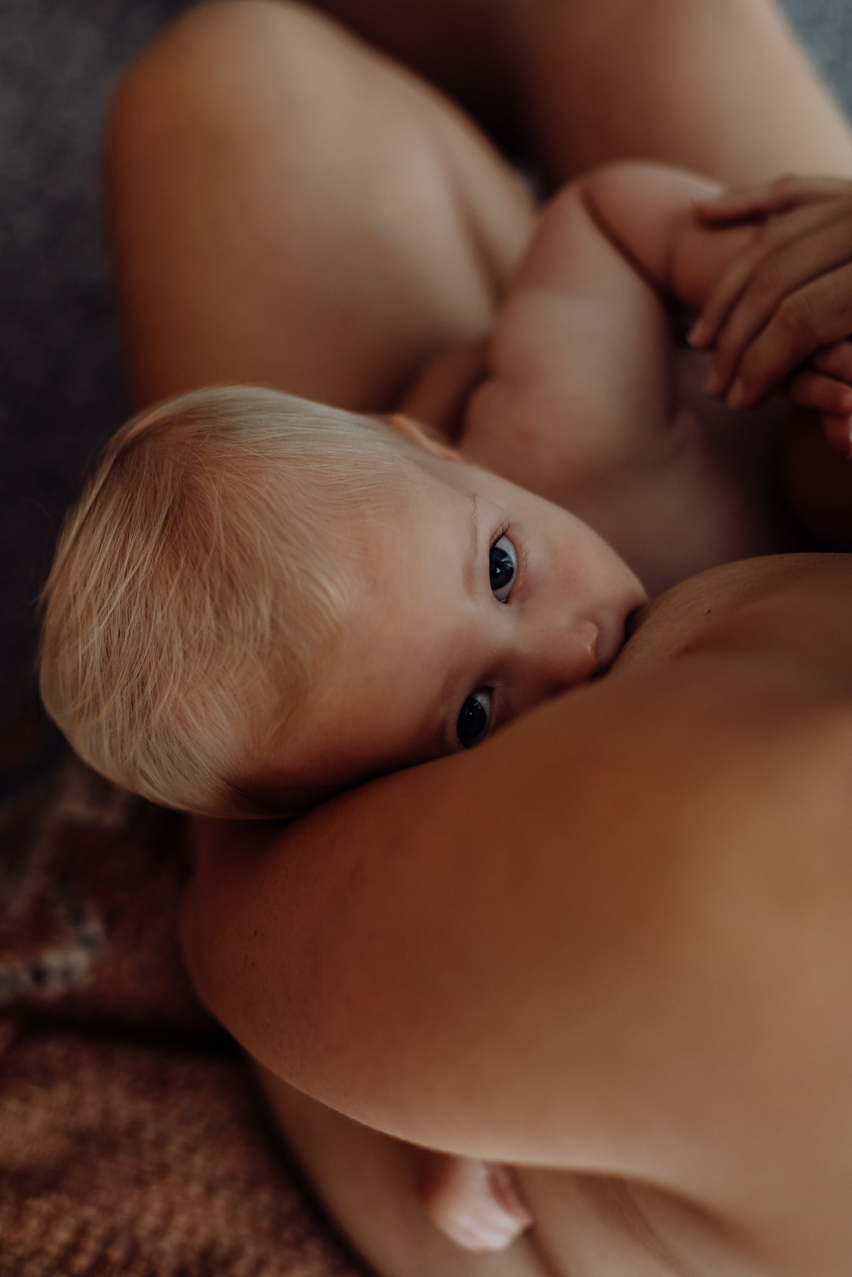 Candid image of a mum breastfeeding her baby in a relaxed family photography session in Mackay QLD