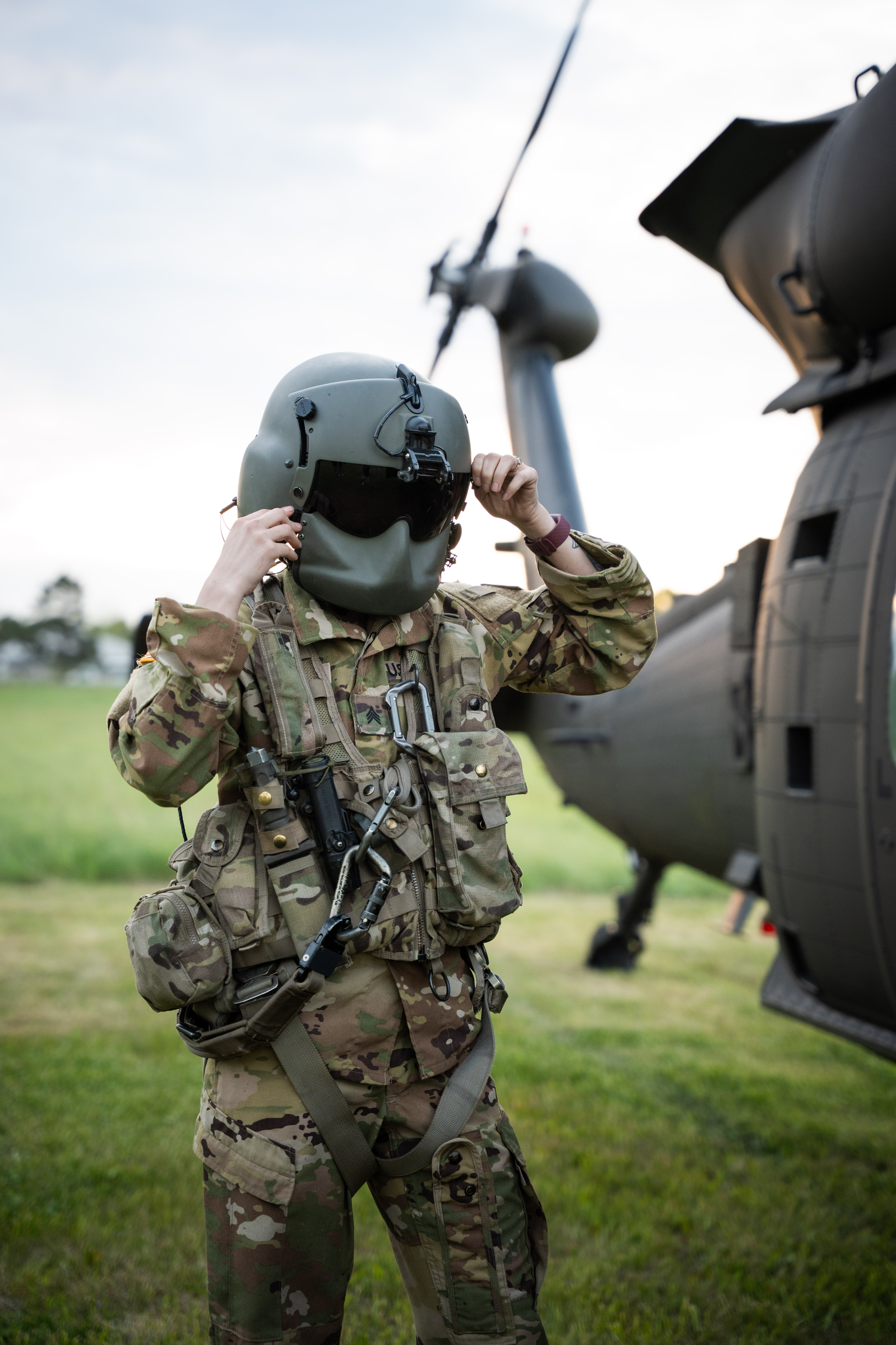 Man with glasses and tied-back hair writing at a desk while looking at a tablet.