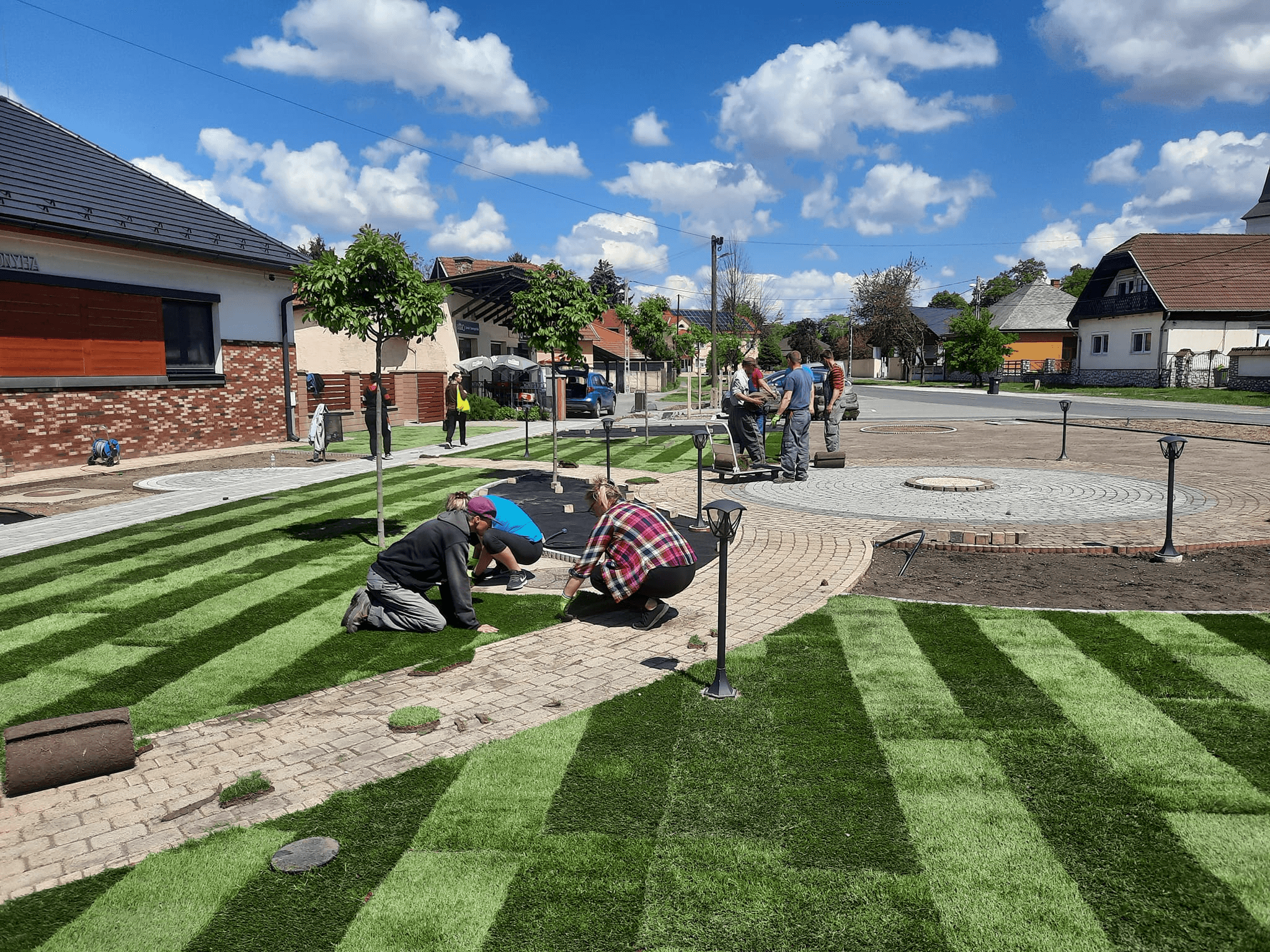 Díszgyep telepítés köztéri parkban kanyargó járdával és a csapat