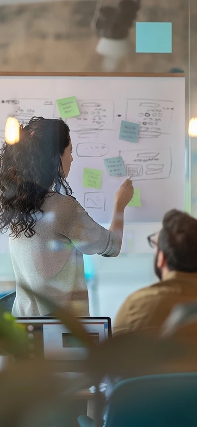 Product designer mapping out user flows and wireframes on a whiteboard during a strategic MVP workshop. The session focuses on transforming complex startup technology into a clear, investable asset to prepare for pre-seed fundraising