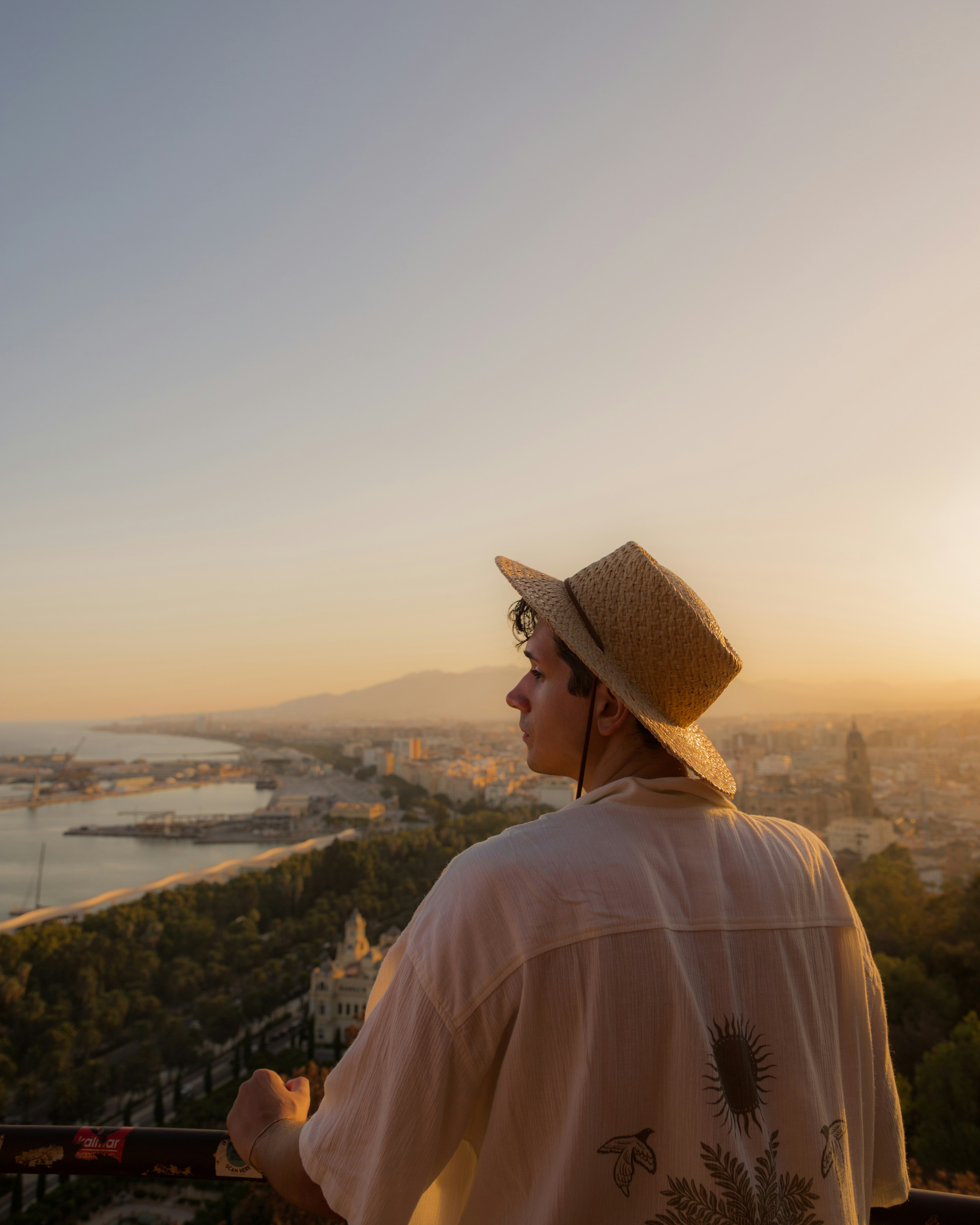 A man wearing a hat looking out over a city
