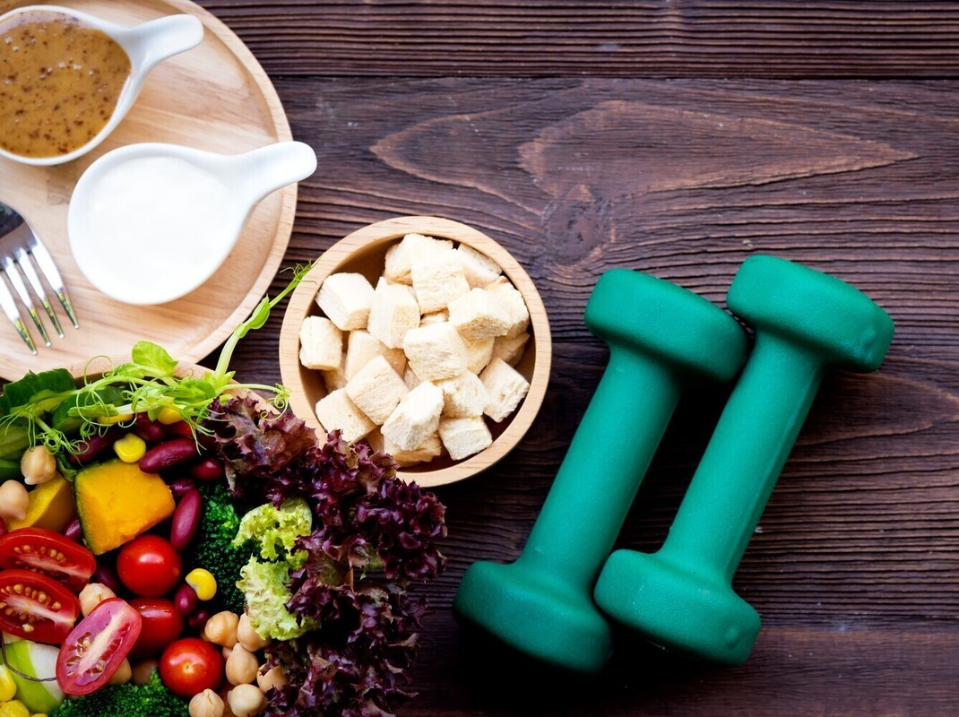closeup of healthy food next to dumbbells for fueling workout routines to lose weight