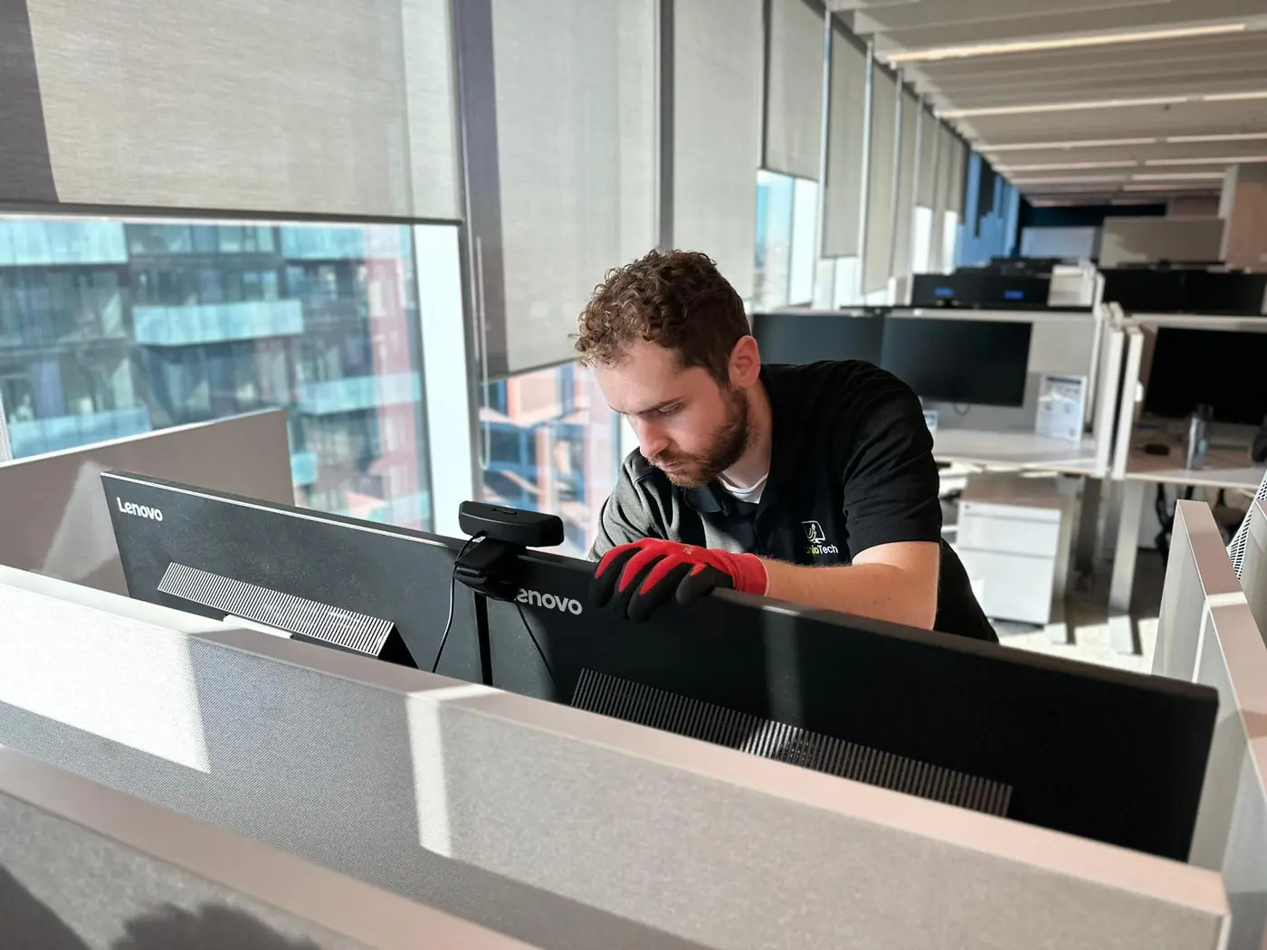 Professional IT technician installing dual monitors and workspace setup in a corporate office.