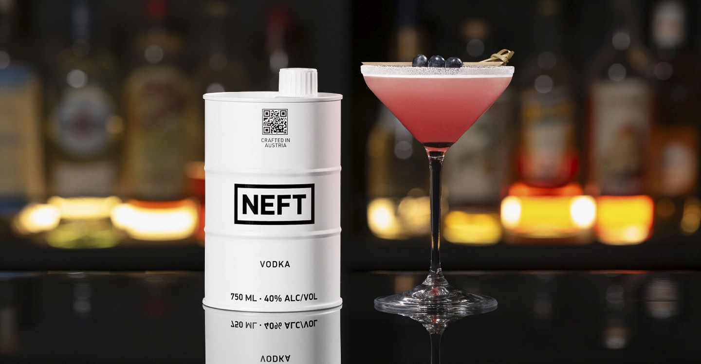 A NEFT Barrel and a glass of Blueberry Lemon Drop on a bar counter.