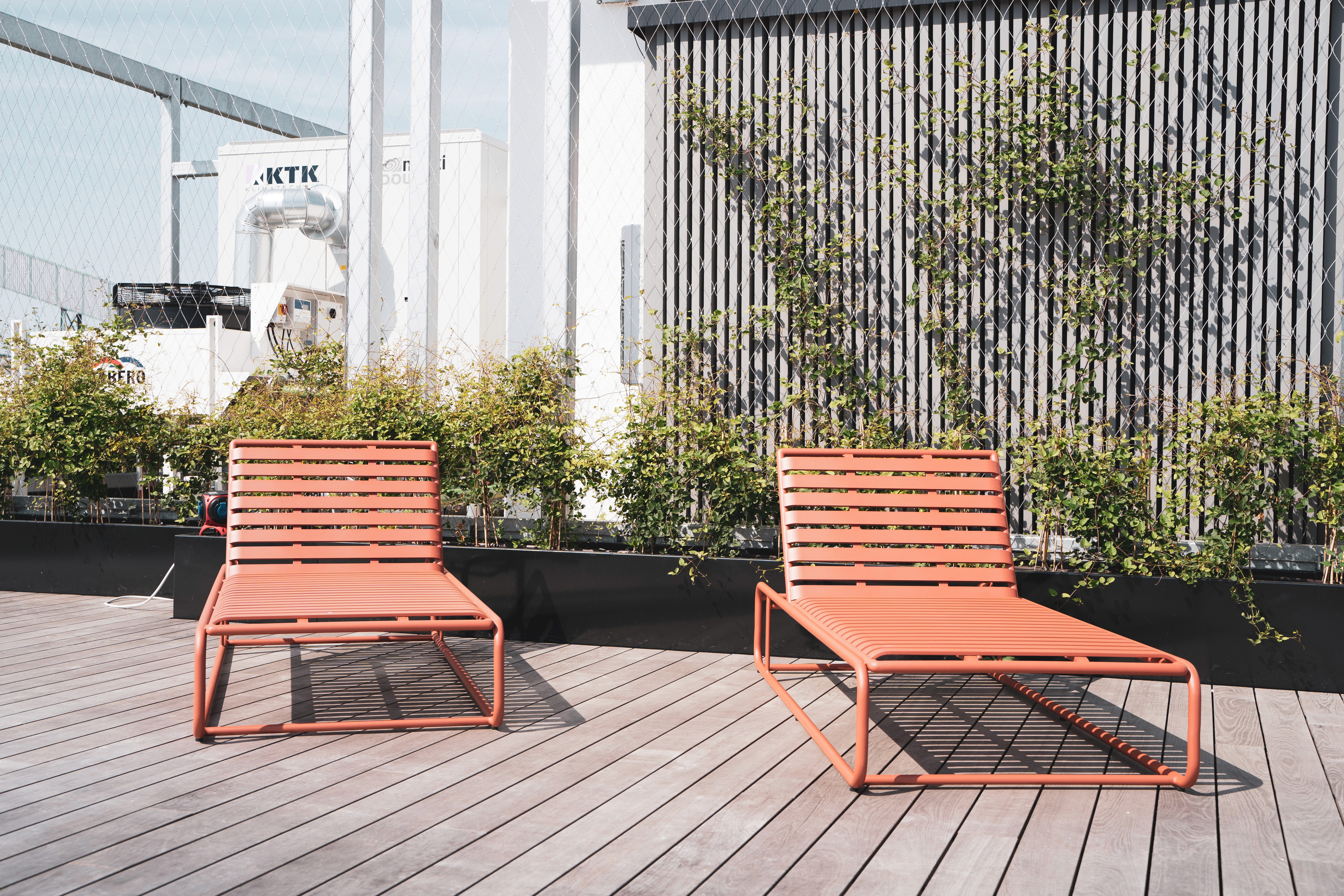 Sonnige Terrasse mit Holzliegen und Pflanzen. Raum für entspannte Pausen und kreatives Arbeiten im Freien.
