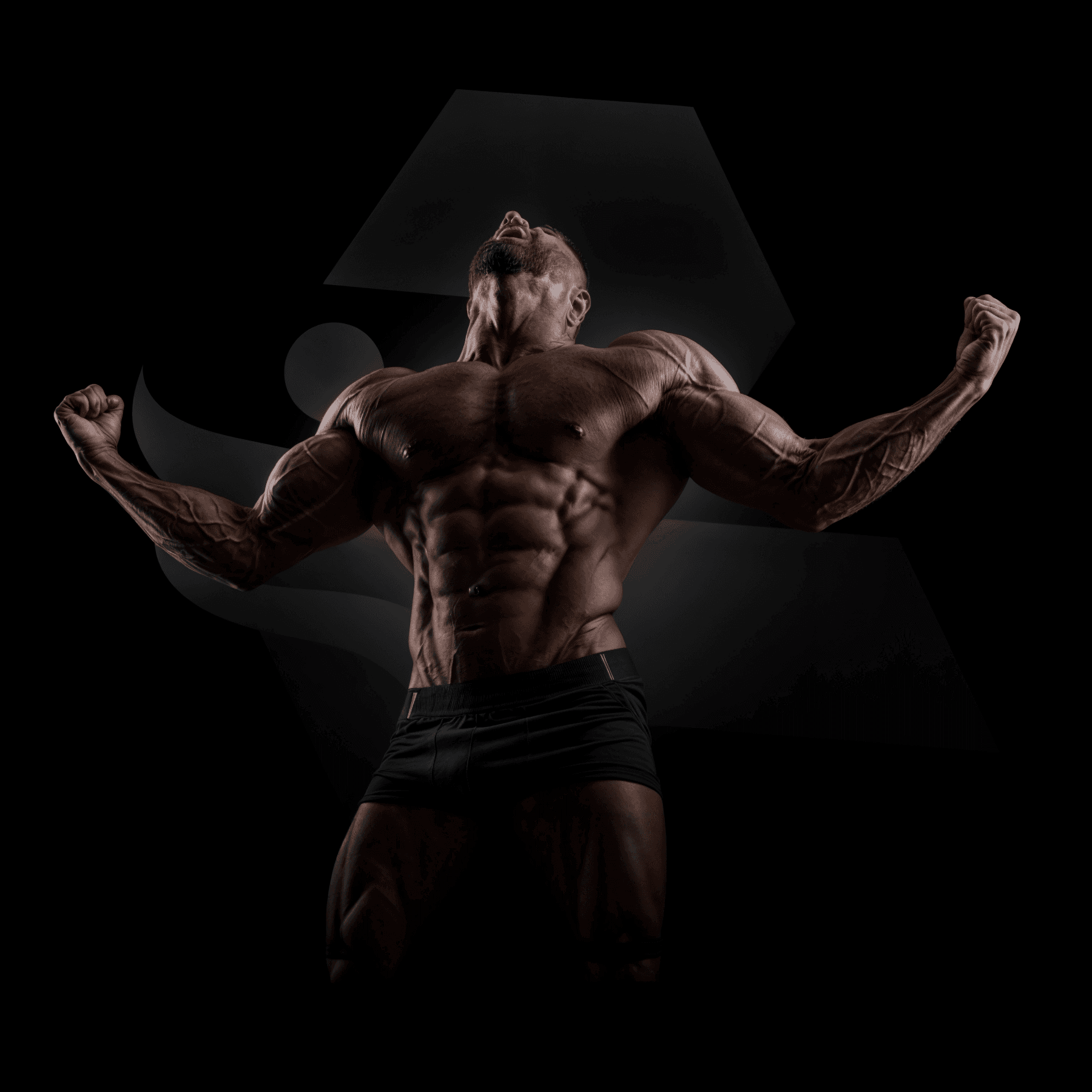 A muscular man flexing his well-defined arms and back muscles against a dark background. He is wearing black athletic shorts, and his powerful pose highlights the results of dedicated strength training and bodybuilding.