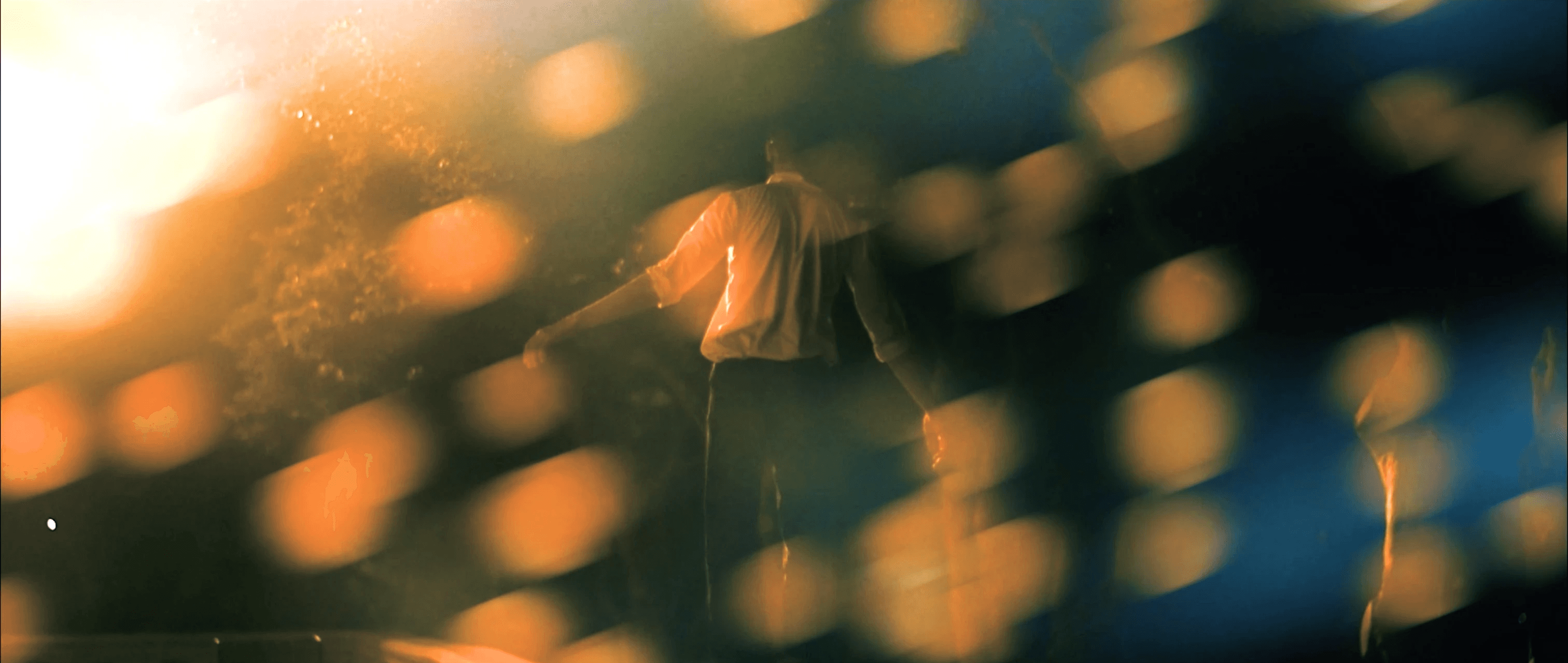 a man walking with his arms stretched with yellow lens flares blurring the shot