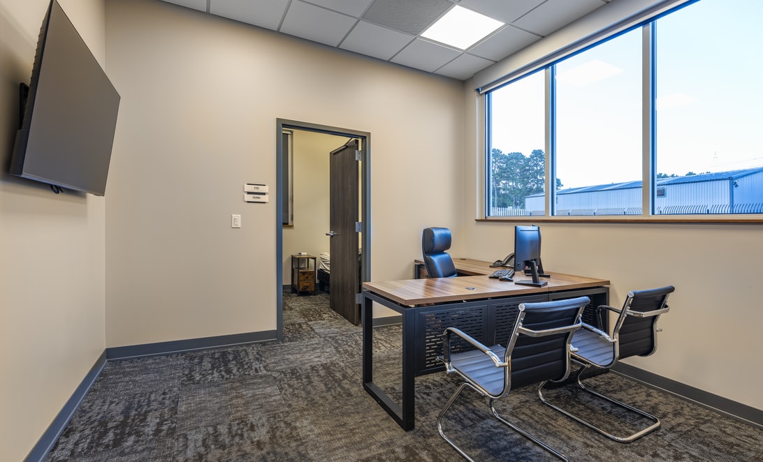 Office with a desk, seating, and corner windows at Spring Fire Station 72, by Martinez Architects