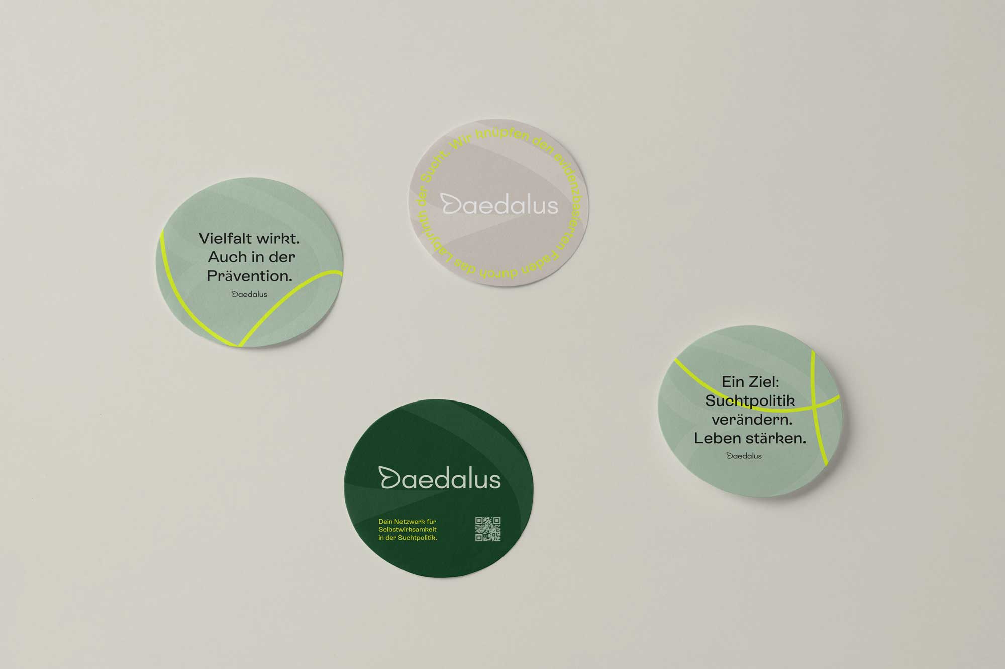 Vier Runde Sticker in salbeigrün, dunkelgruen und beige mit gelben Linienakzenten und Schrift