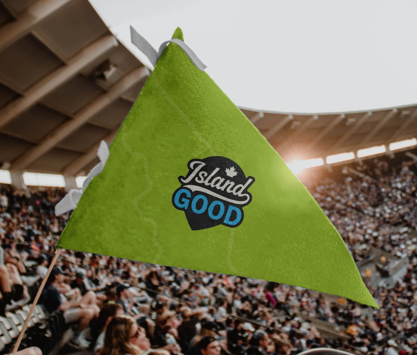 The Island Good flag on a lime green pennant in a stadium full of people.