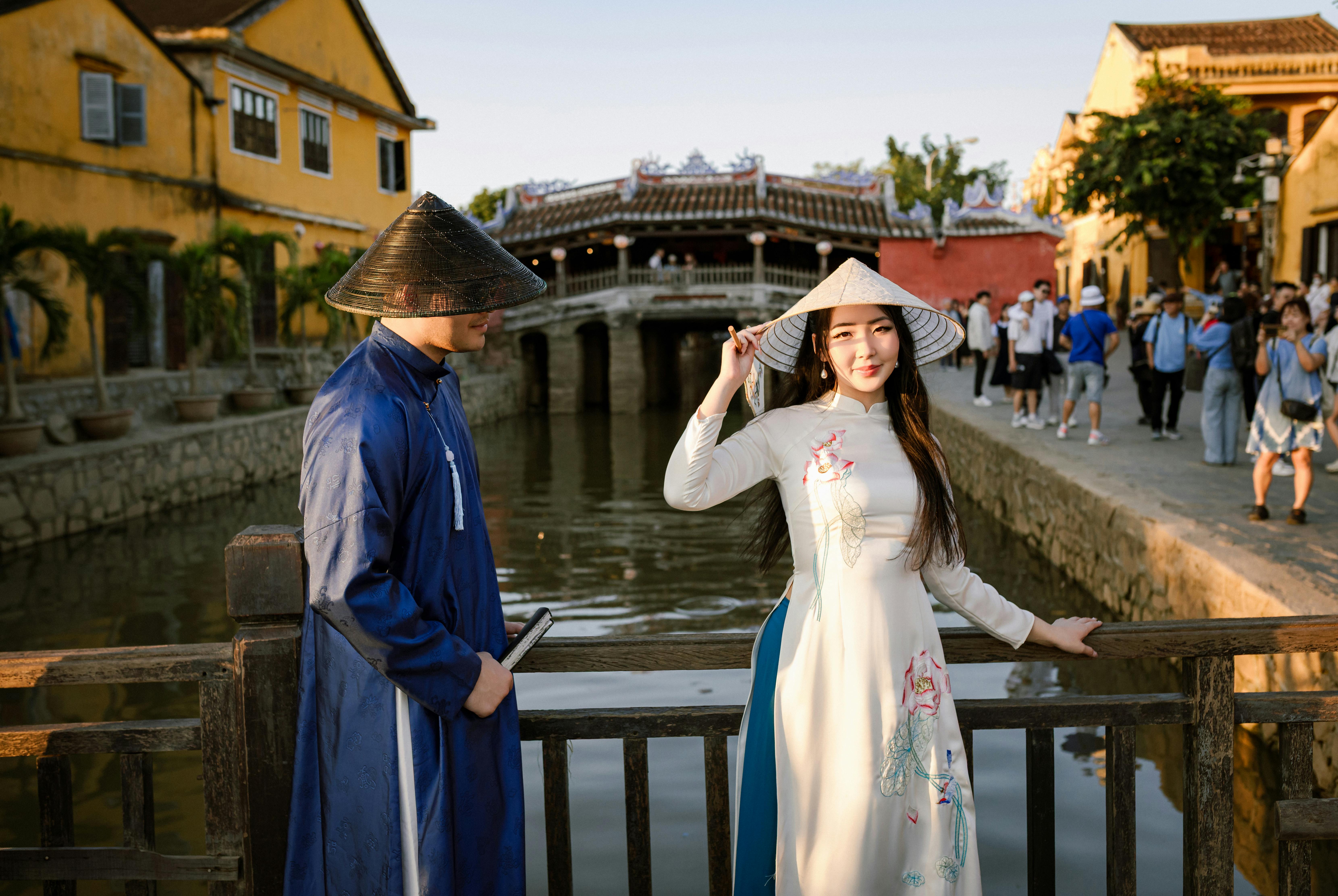 Couple in traditional Vietnamese dress near iconic Hoi An bridge, capturing cultural heritage