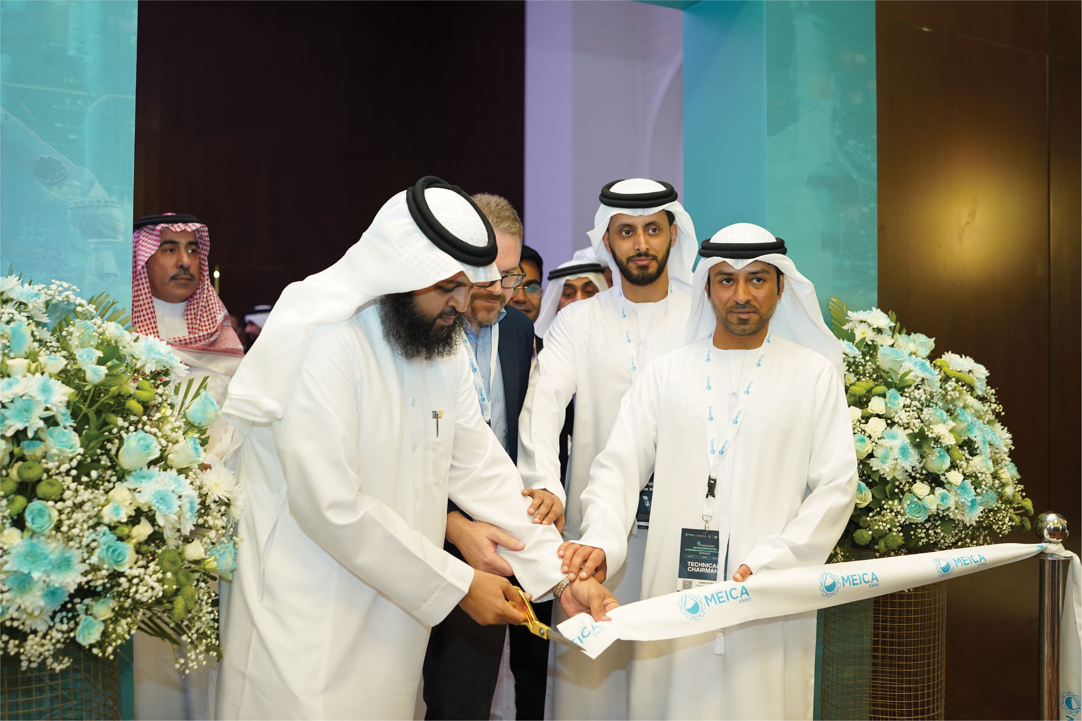 Confident male speaker in a white shirt and headset mic gesticulates on stage with teal spotlighting.