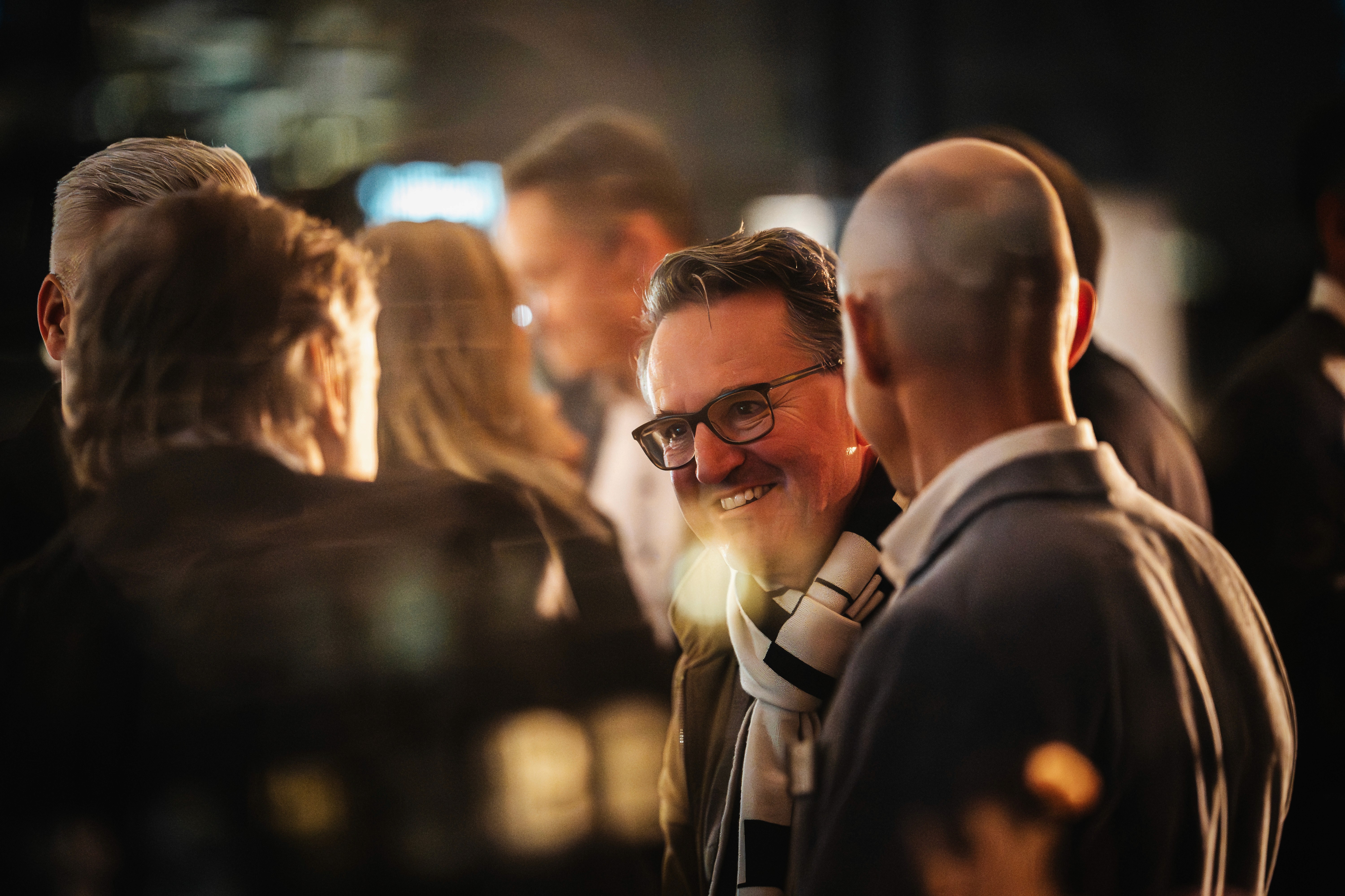 People crossing a busy street with cars and buildings.