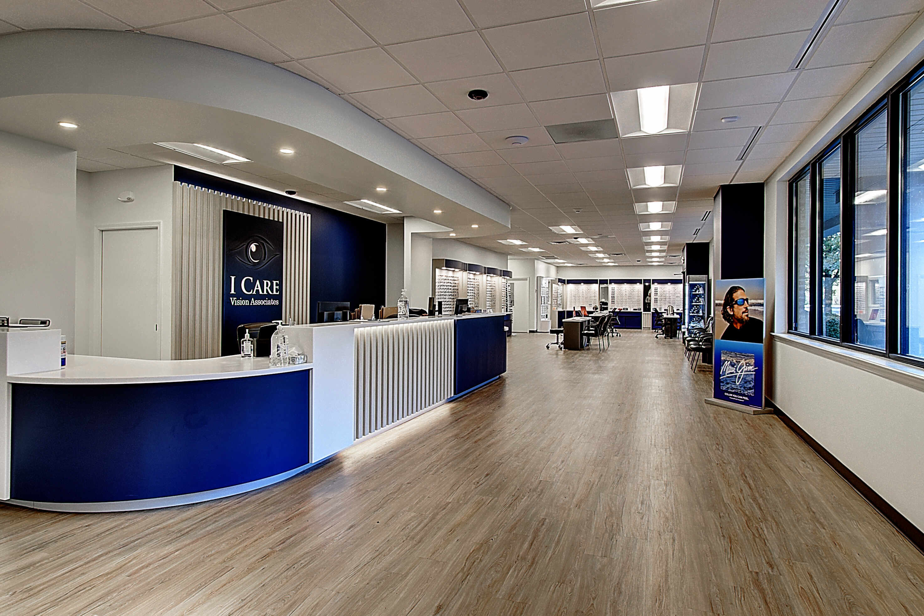 Modern office reception area with blue and white decor, wooden floors, and large windows providing natural light.