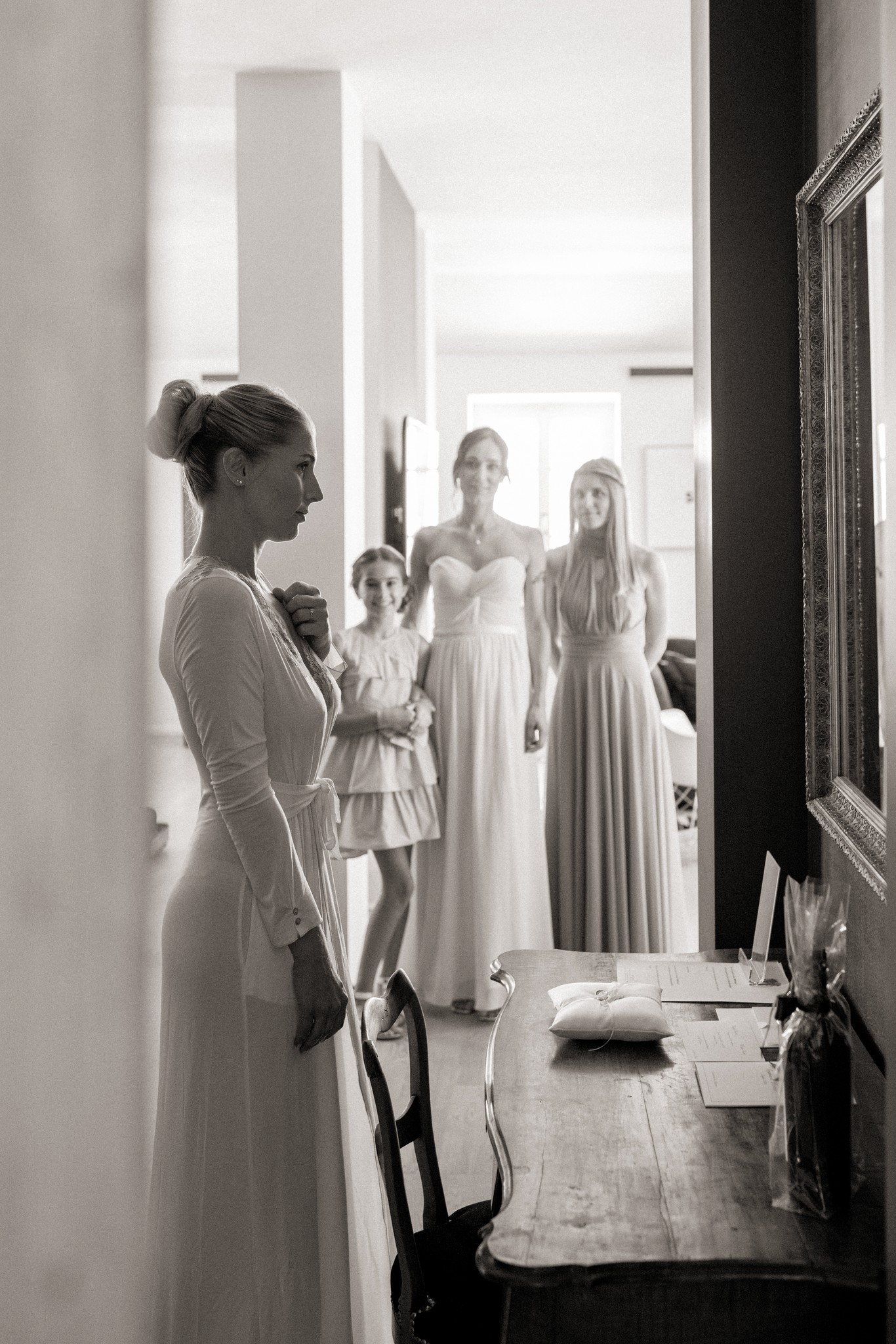 Sposa di profilo ai preparativi davanti allo specchio, damigelle in abiti chiari a Villa Malenchini