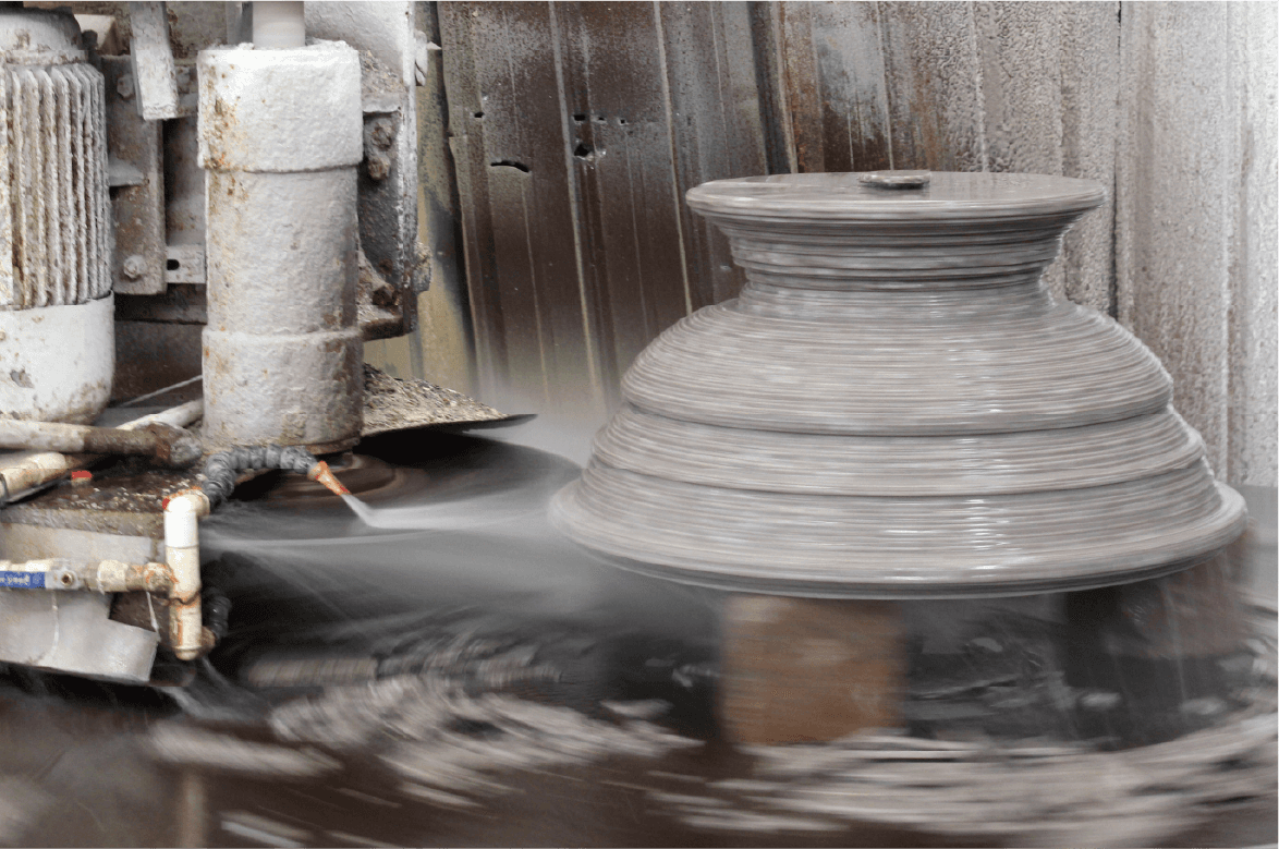 Close-up of the Column Cap & Base Profiling Machine in action, carving intricate designs on a large stone piece, demonstrating precision and craftsmanship.