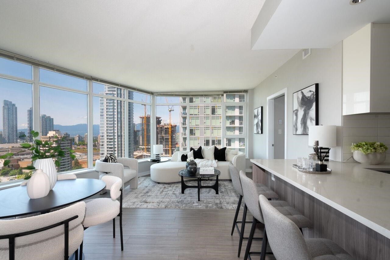 A modern kitchen with large windows offering city views, featuring sleek furnishings and a minimalist design.