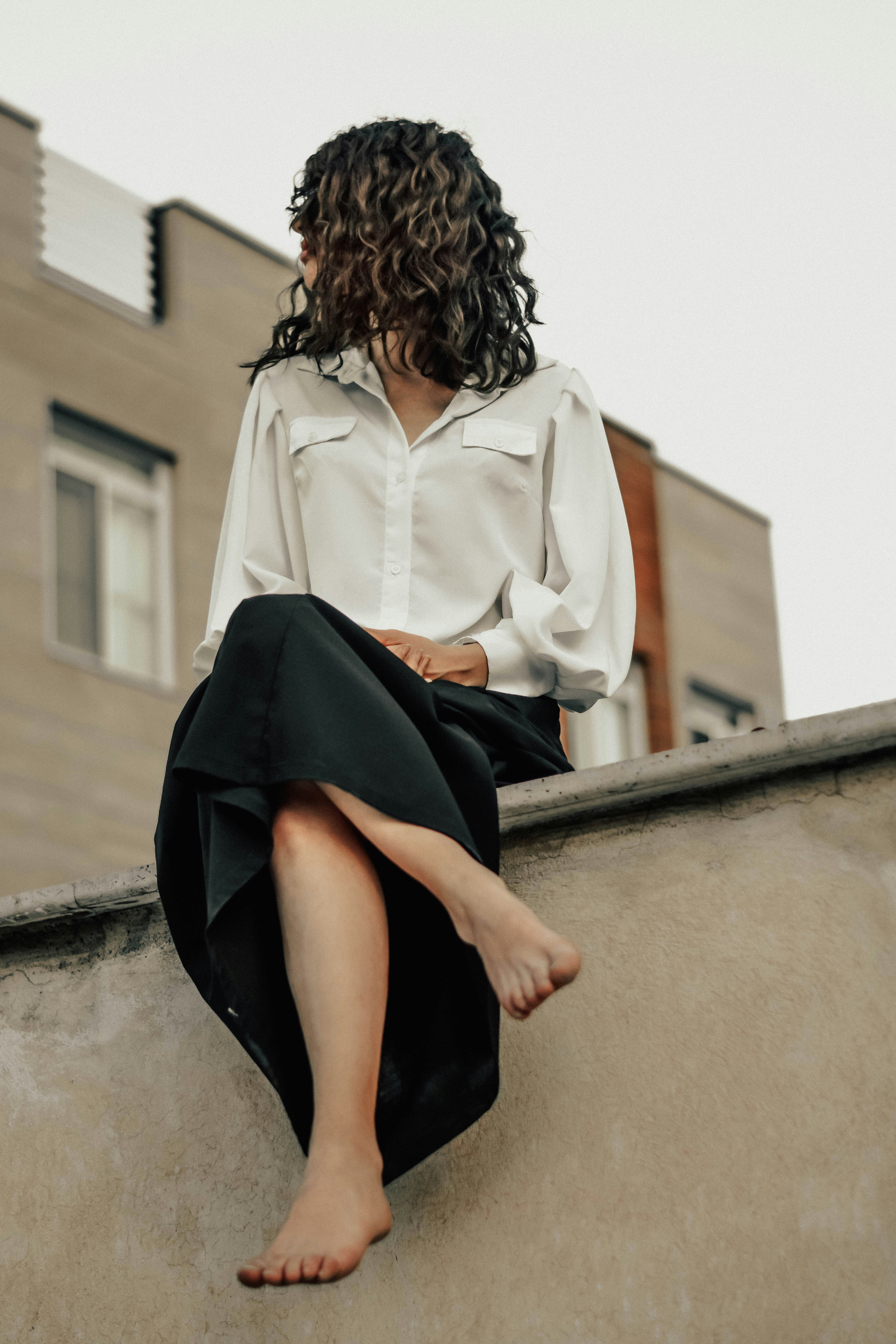 a woman sitting on a ledge with her legs crossed