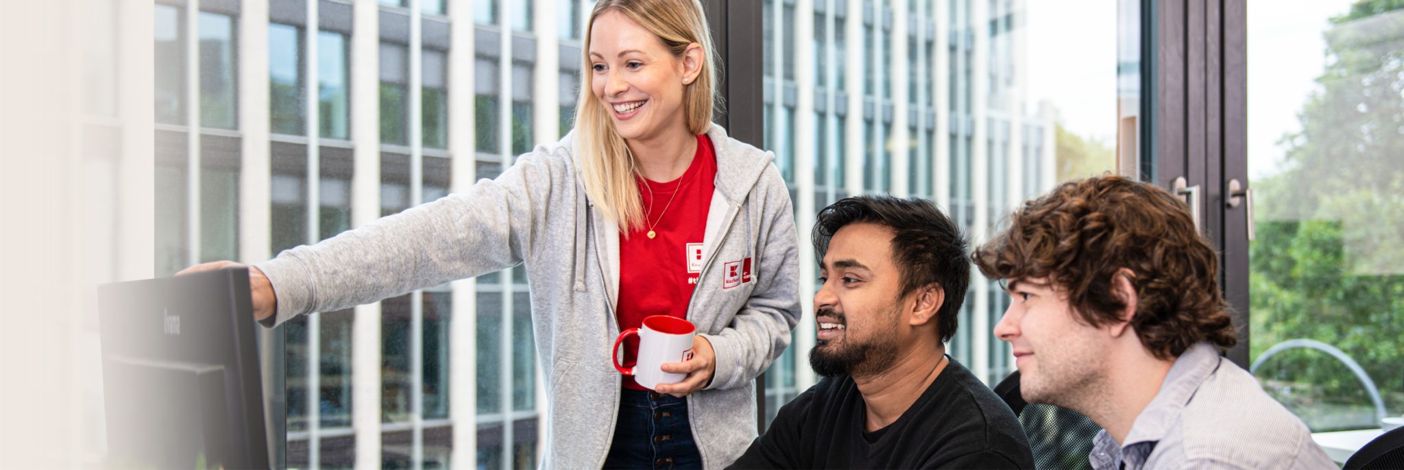 Three young people at Kaufland e-commerce looking at a screen
