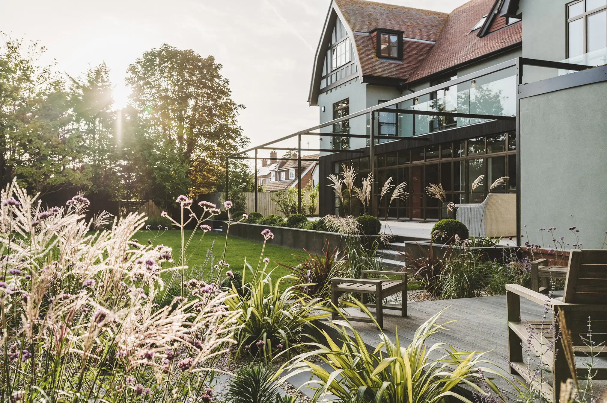 A sunny garden with vibrant greenery, a cozy house, and a patio, creating a serene outdoor space.