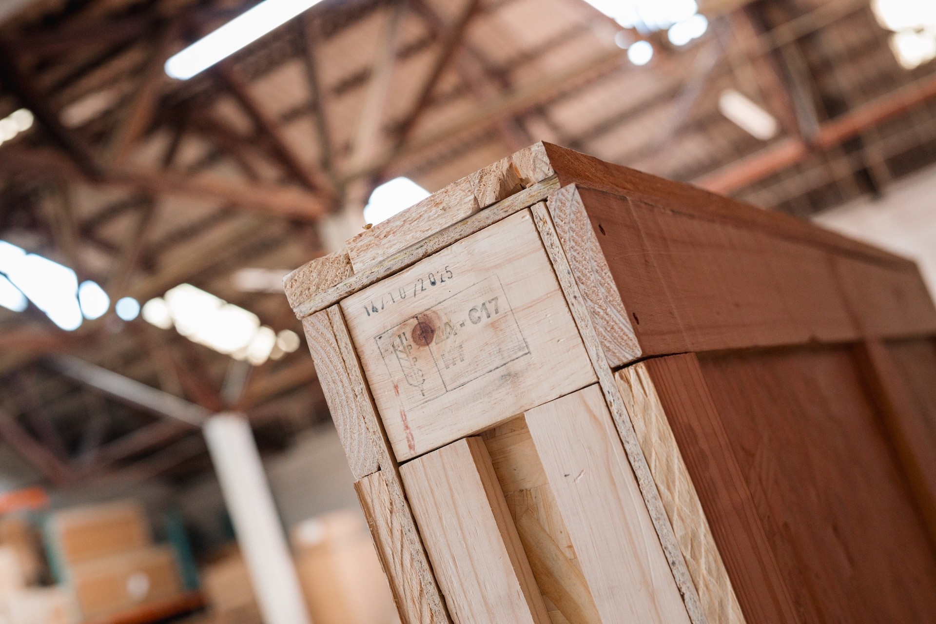 Forklift operator moving a large custom wooden export crate in a warehouse.