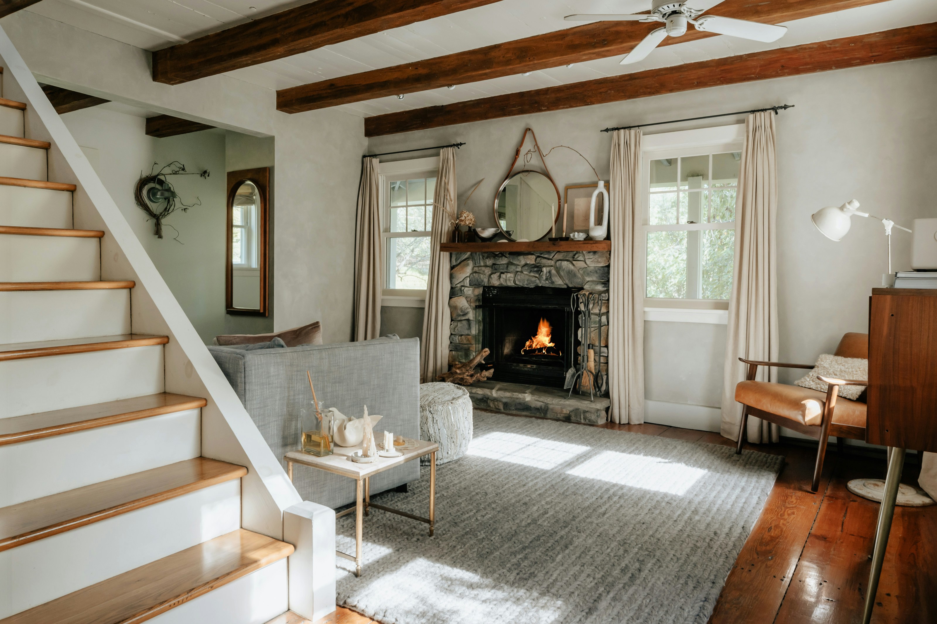 A white farmhouse living room with a fireplace and a staircase