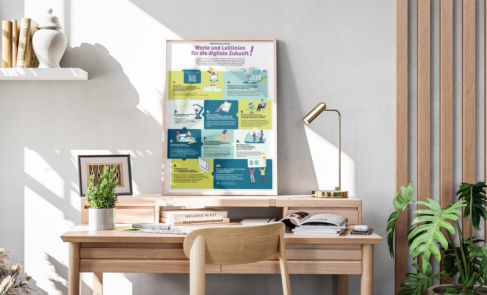 A3-Poster mit den zehn Leitlinien der Digitalstrategie 2025+ der Evangelisch-Lutherischen Nordkirche, auf einem Schreibtisch mit Lampe, Pflanze und Dekoration platziert.